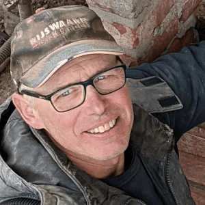 Andre Schermutzki in Arbeitskleidung vor Klinkermauerwerk.